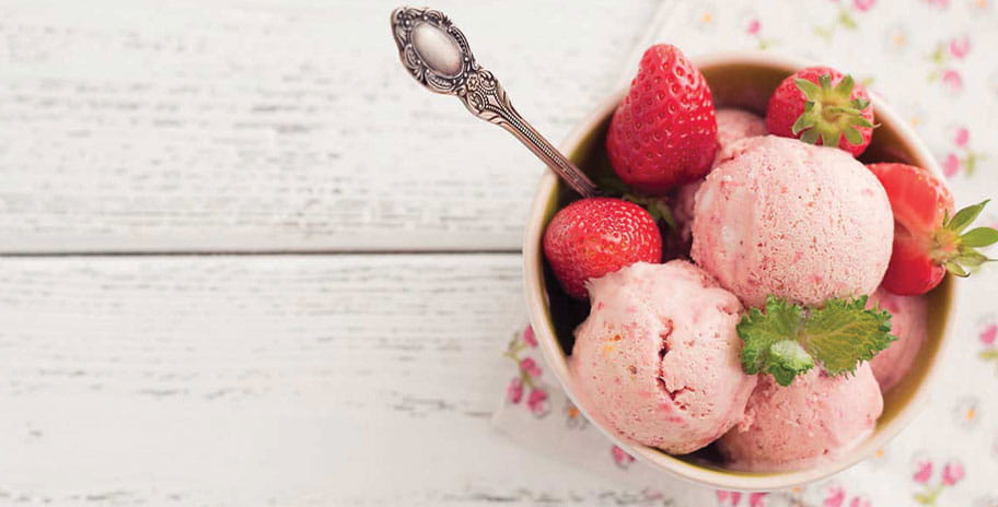 Scoops of strawberry jam in a bowl with fresh strawberries