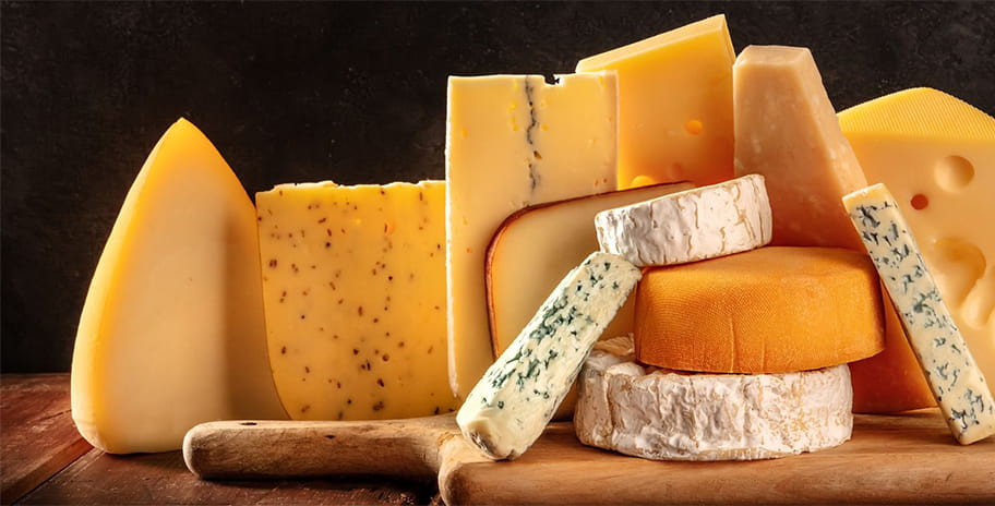 A selection of cheeses on a wooden cutting board and table