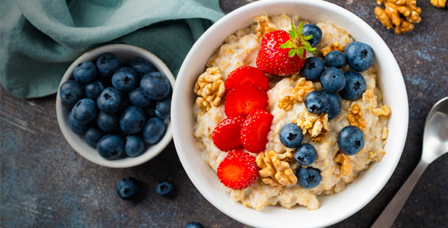 Image of a bowl of oats with some berries on top and another small serving of blueberries next to it. 
