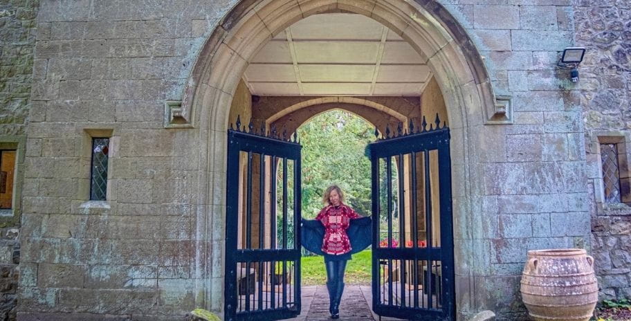 The writer holding open the giant gates to the castle where she lives