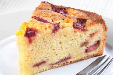 Close up of a slice of rhubarb and custard cake on a plate with a cake fork