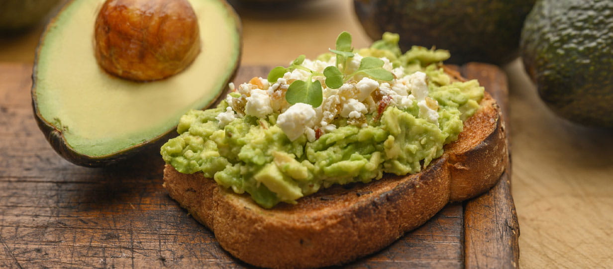 Roughly mashed avocado on toast topped with crumbled feta