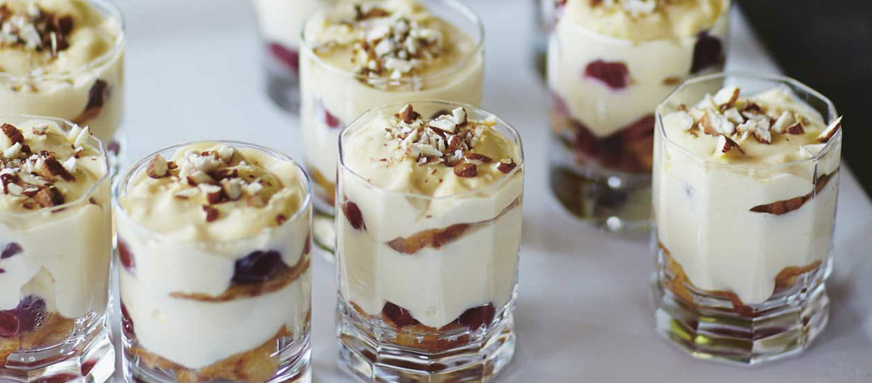 Layered dessert in glass cups topped with chopped nuts
