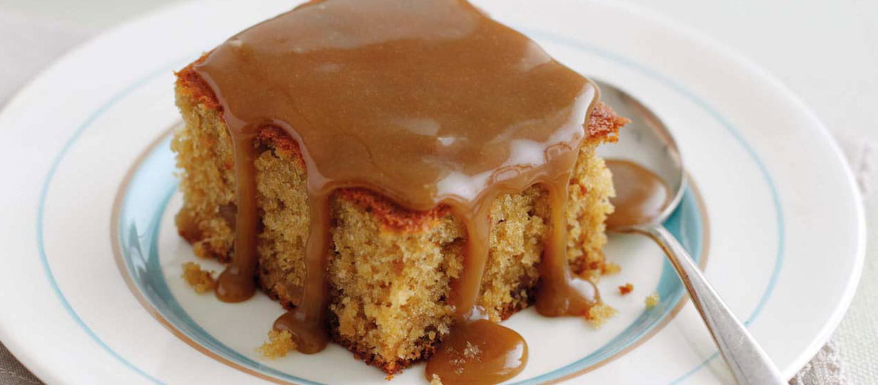 A square of sticky toffee pudding served on a white plate