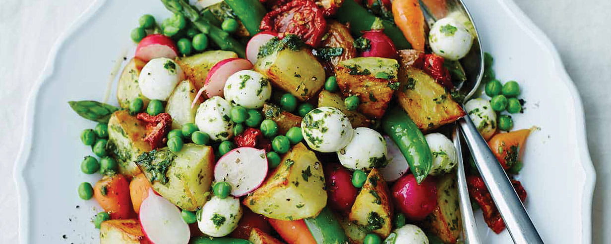 A colourful plate with peas, sun dried tomatoes, roast potatoes, radish, carrots and mozzarella