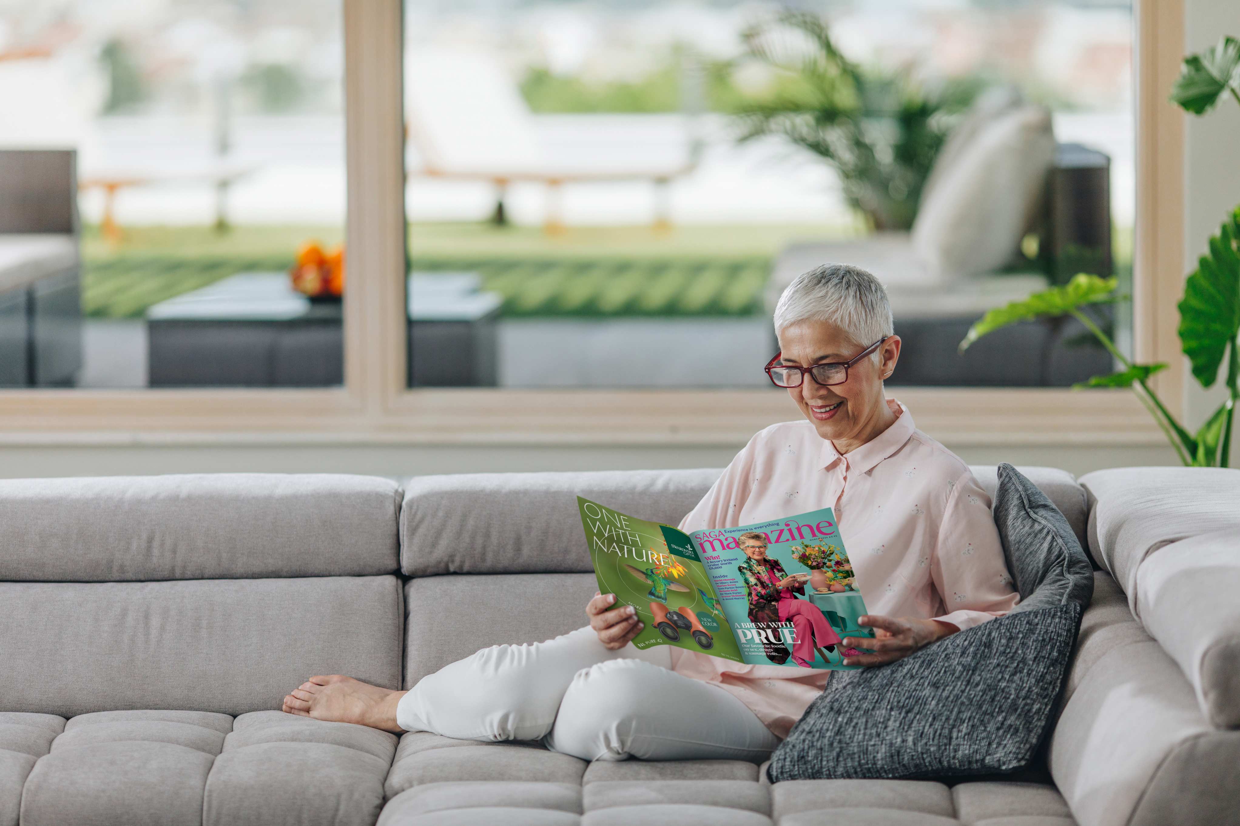 Mature woman on a sofa reading a Saga Magazine