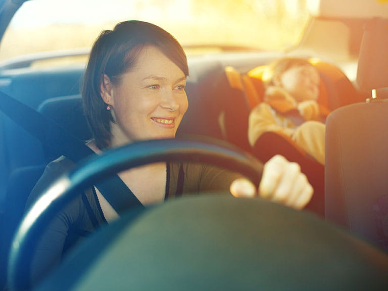 A new mother in a car with her baby asleep in a car seat to represent Parent & Child car parking and the issue of whether disabled drivers should be able to park in a Parent & Child car parking bay