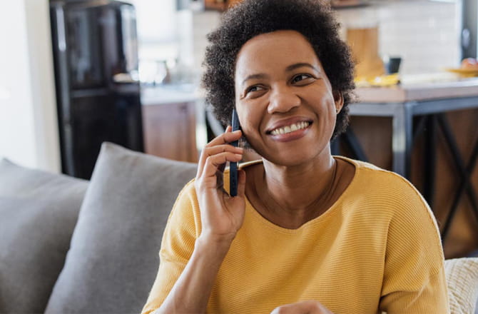 Older person sitting on sofa talking on a mobile phone