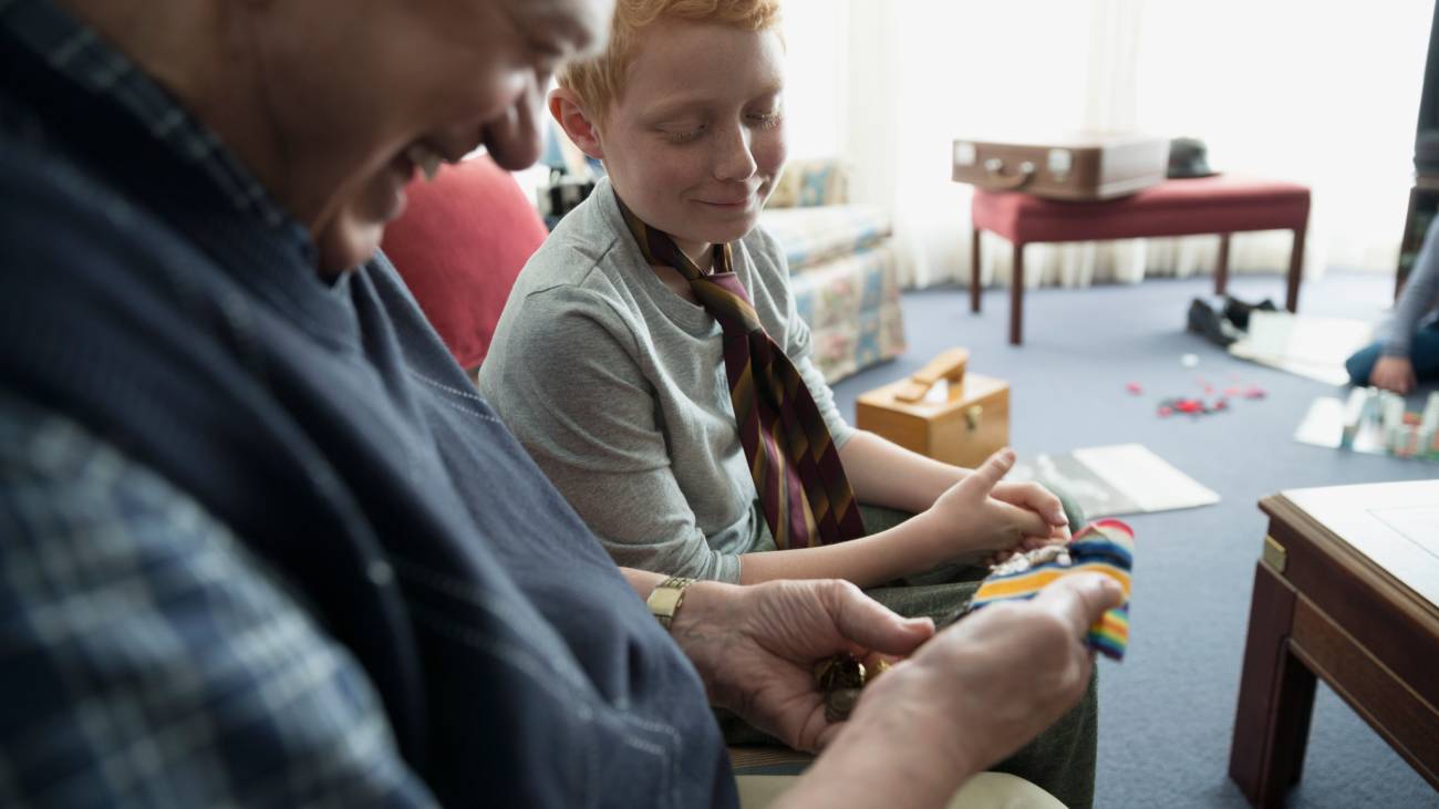 A elder man showing his grandchild a range of medals