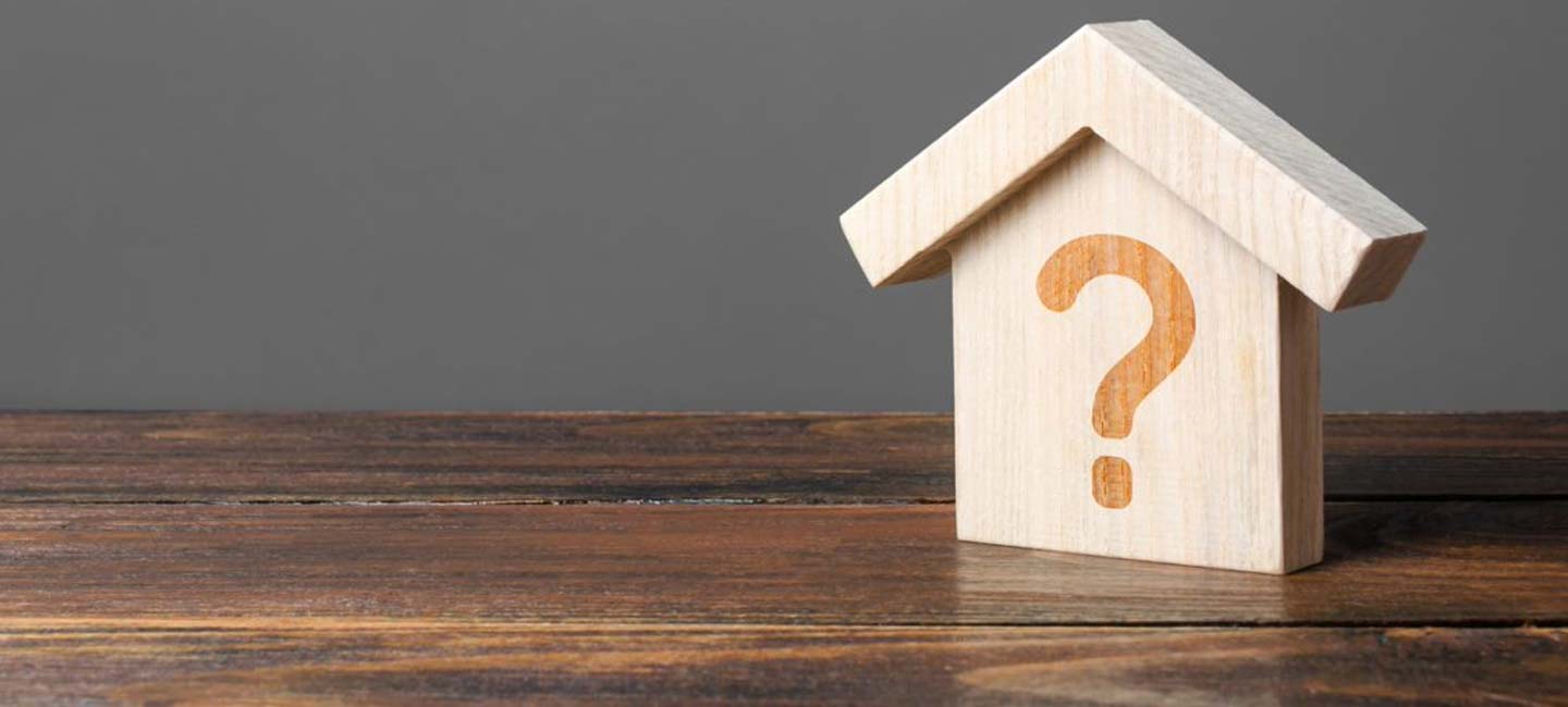 Wooden model of a house with a question mark drawn on it