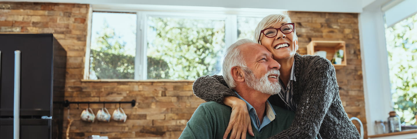 Two people in a kitchen hugging and smiling