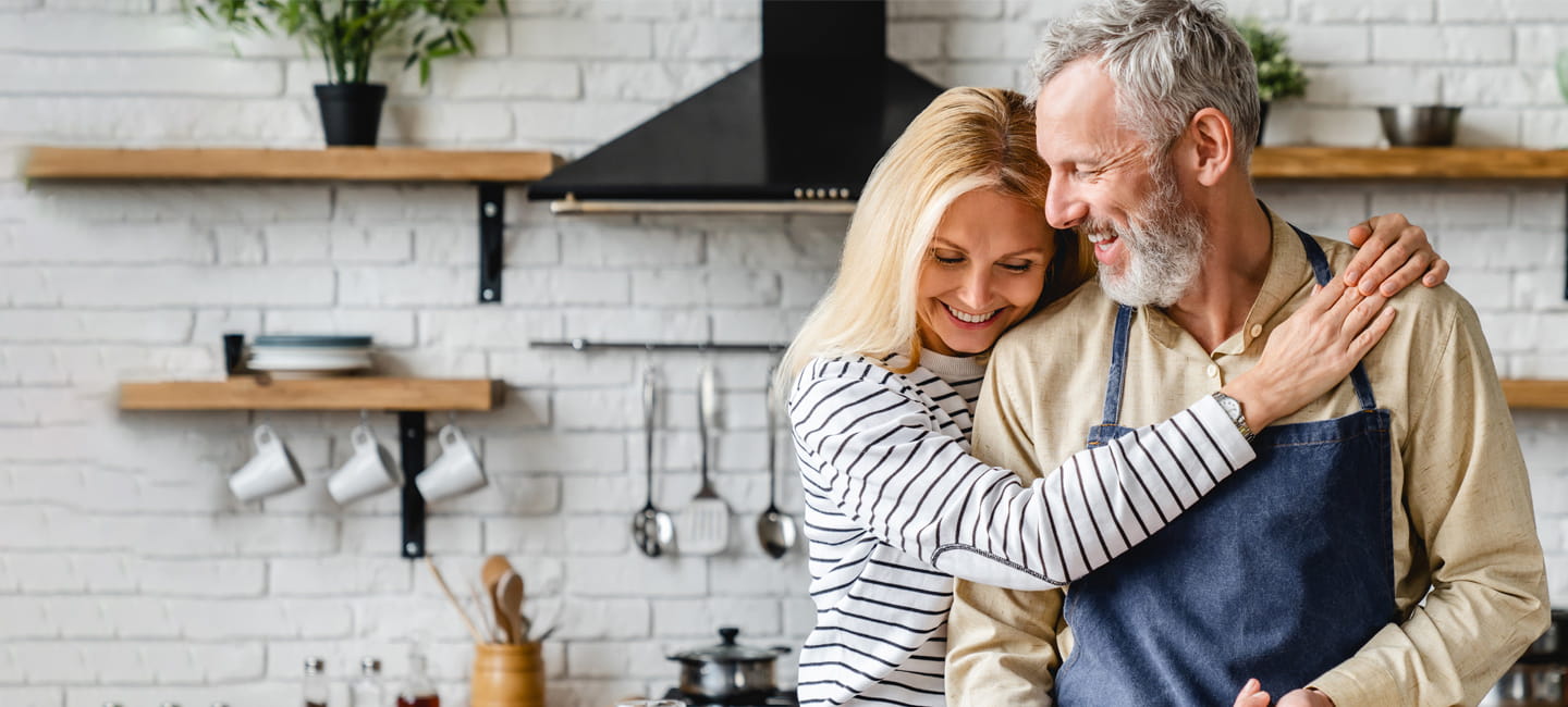 Two people hugging and laughing in a kitchen
