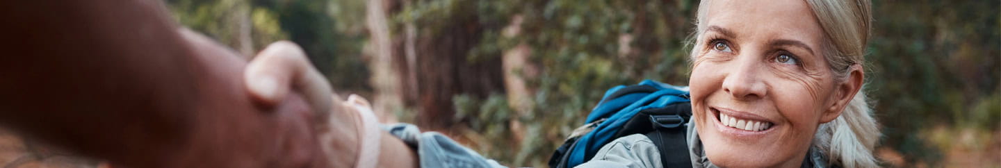 A lady taking an offered helping hand while out hiking