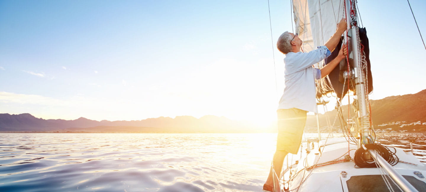 A man on a sailboat at sea working the sails