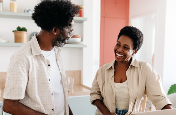 A couple smiling at each other in the kitchen