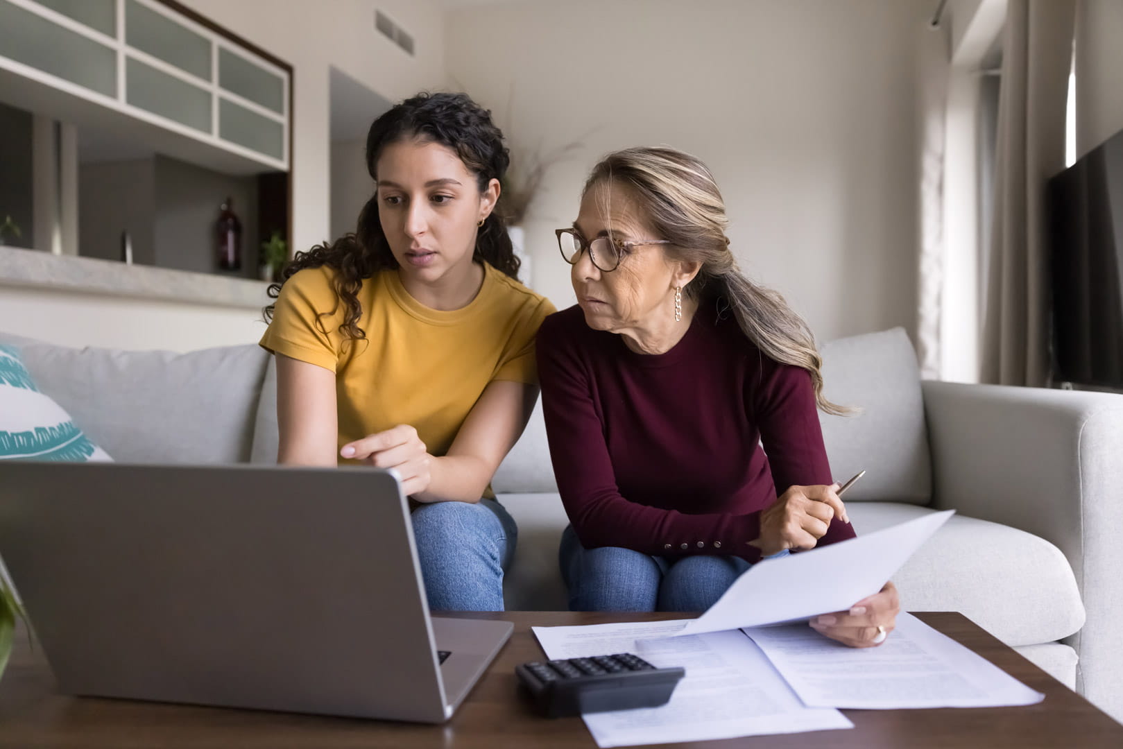 A mother and daughter using a laptop and dealing with paperwork