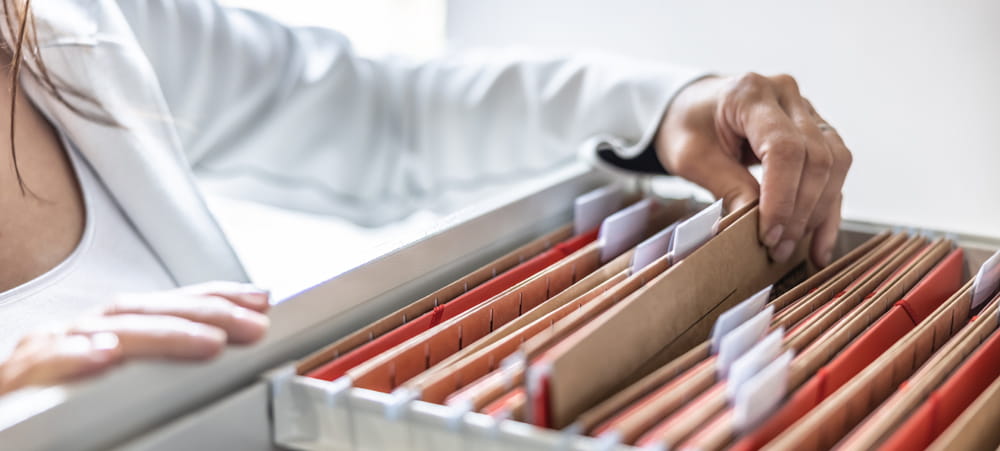 Someone looking through a filing cabinet with hanging files