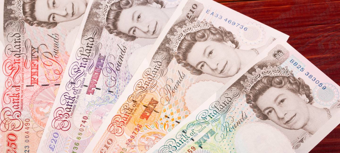 A five, ten, twenty and fifty pound notes place on a brown table