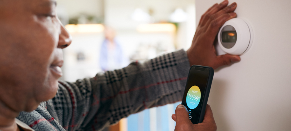 A man checking his wi-fi thermostat with his mobile phone