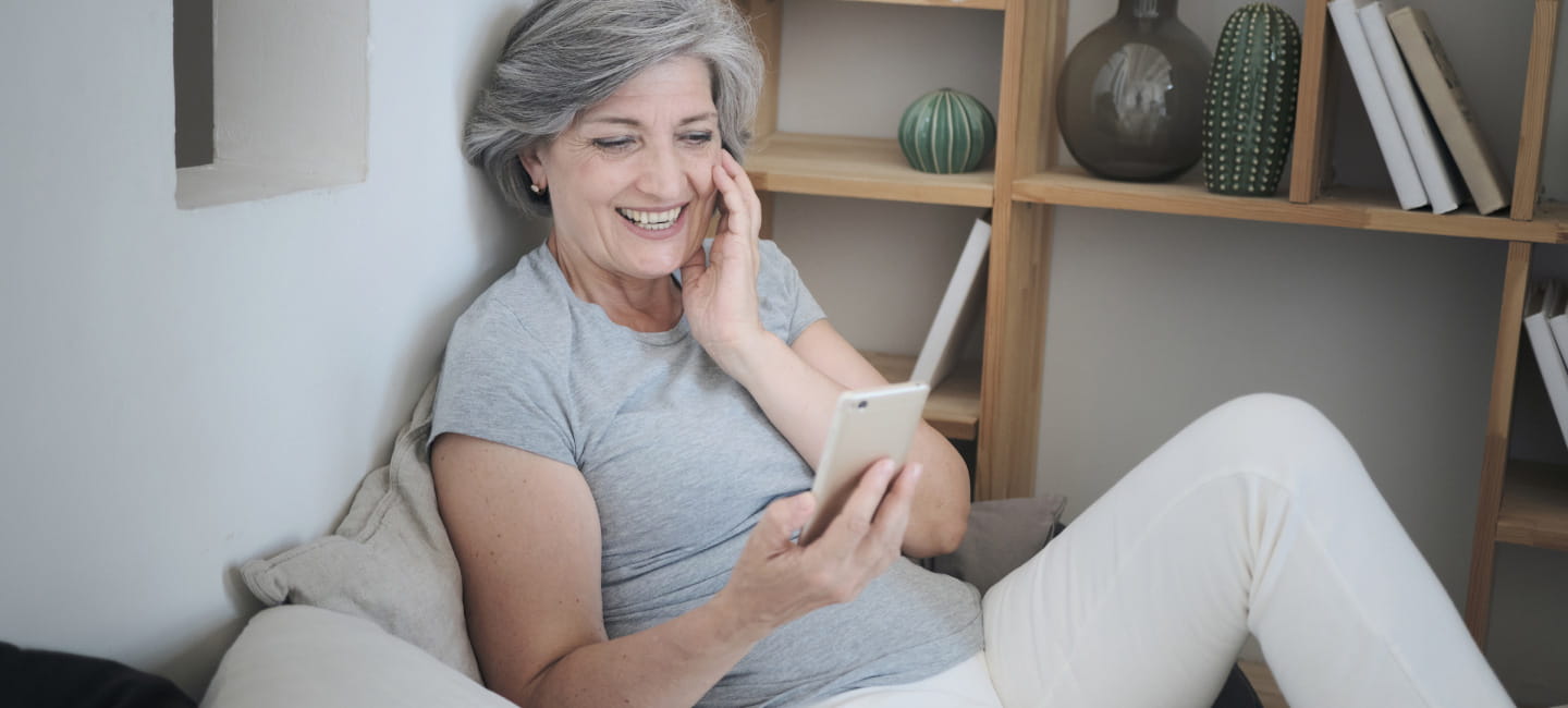 A woman sitting and smiling at her mobile phone