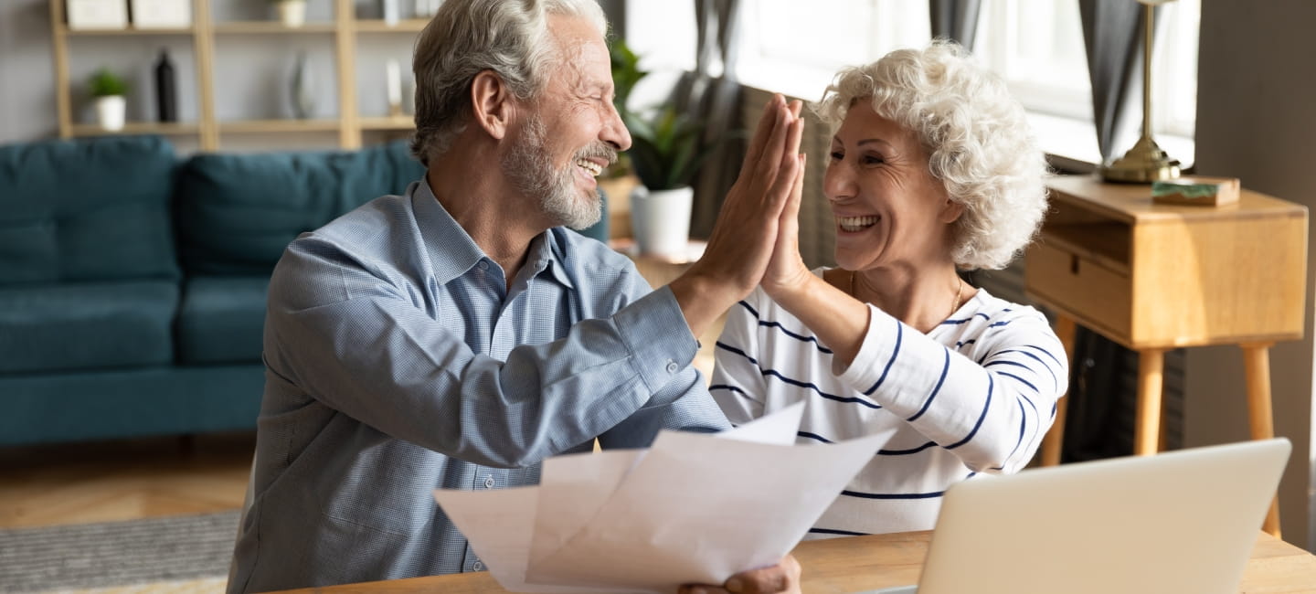 Man and woman sat behind a computer and high fiving each other 