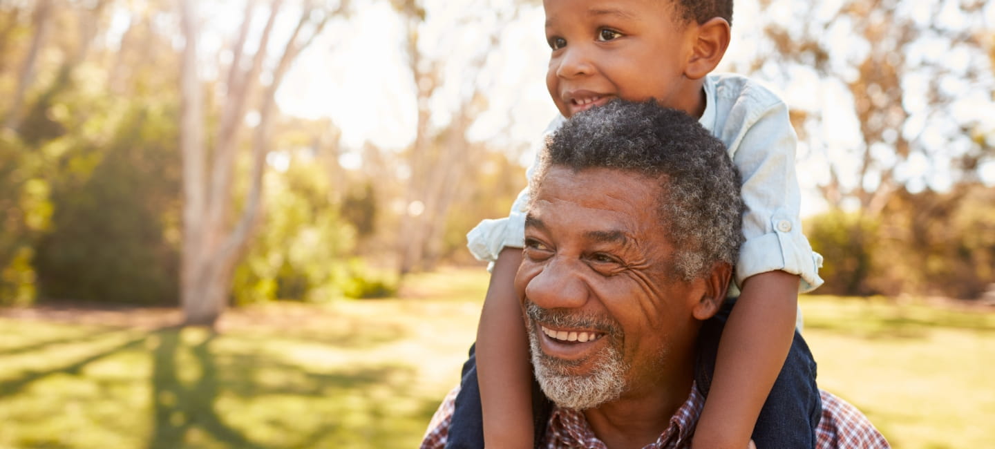 A little boy sitting on his Granddad's shoulders - both are very smiley