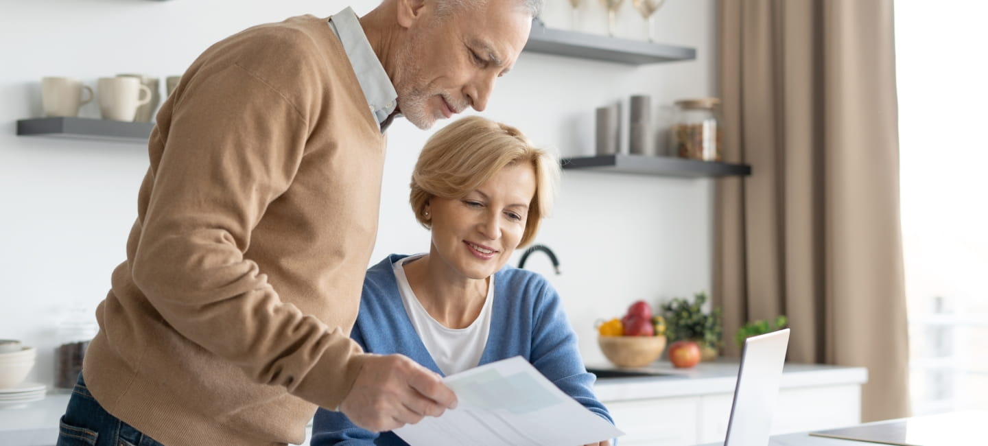 A man and woman looking at paperwork and a laptop