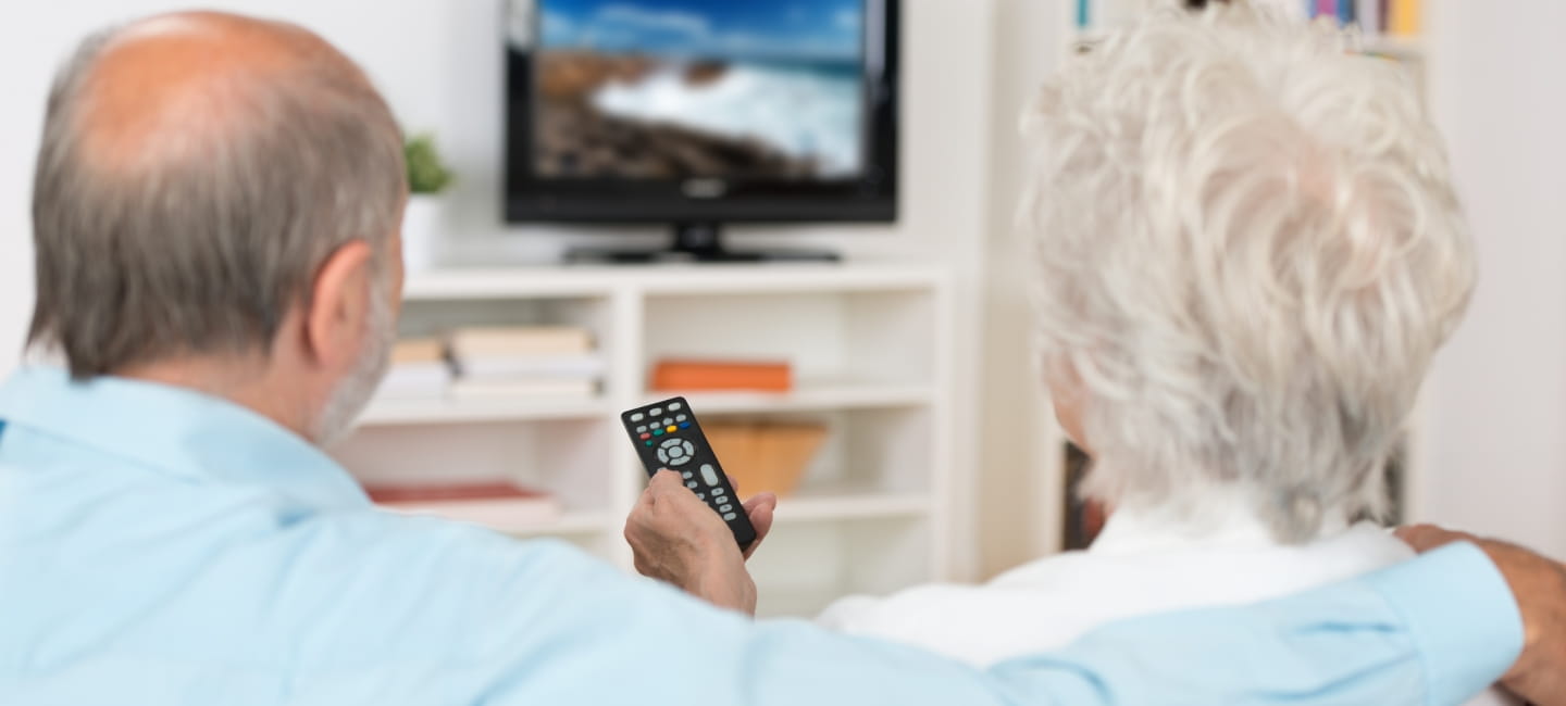A couple sat on the sofa watching the TV 