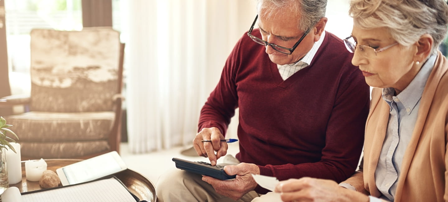 A man and woman sat with paperwork and a calculator