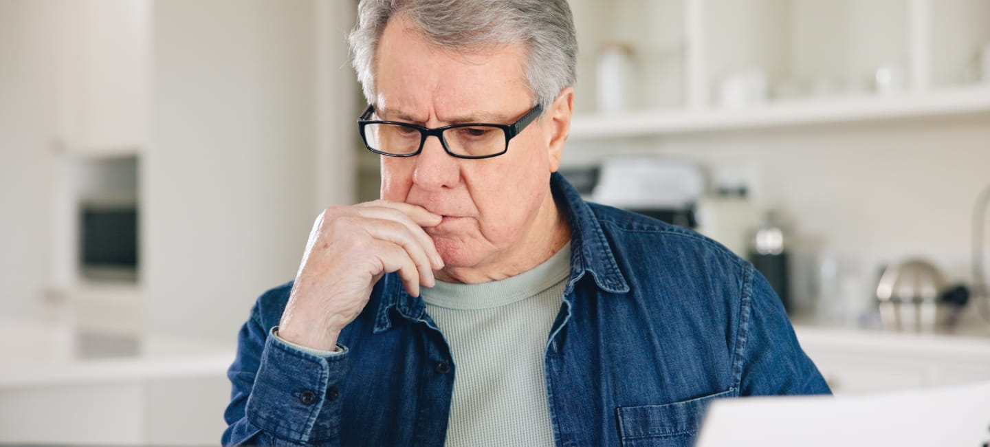 A man pensively looking at his laptop screen