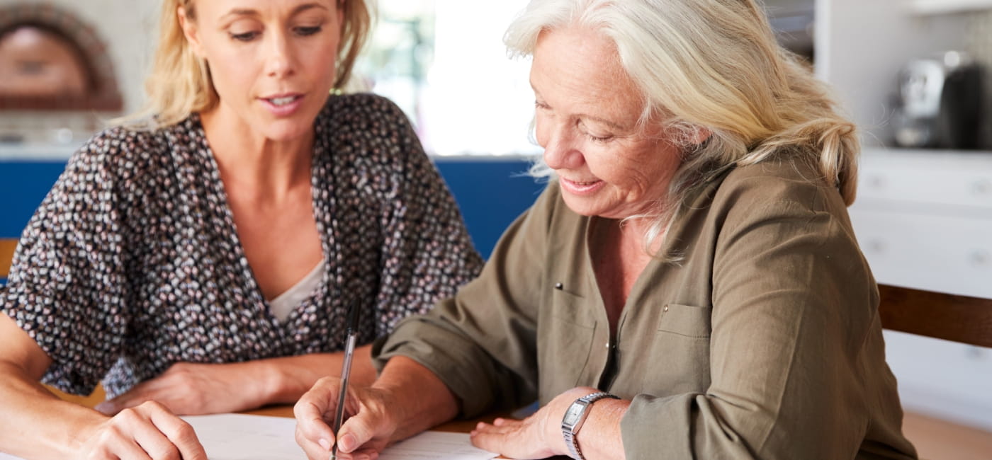 Two women sat at a desk signing papers