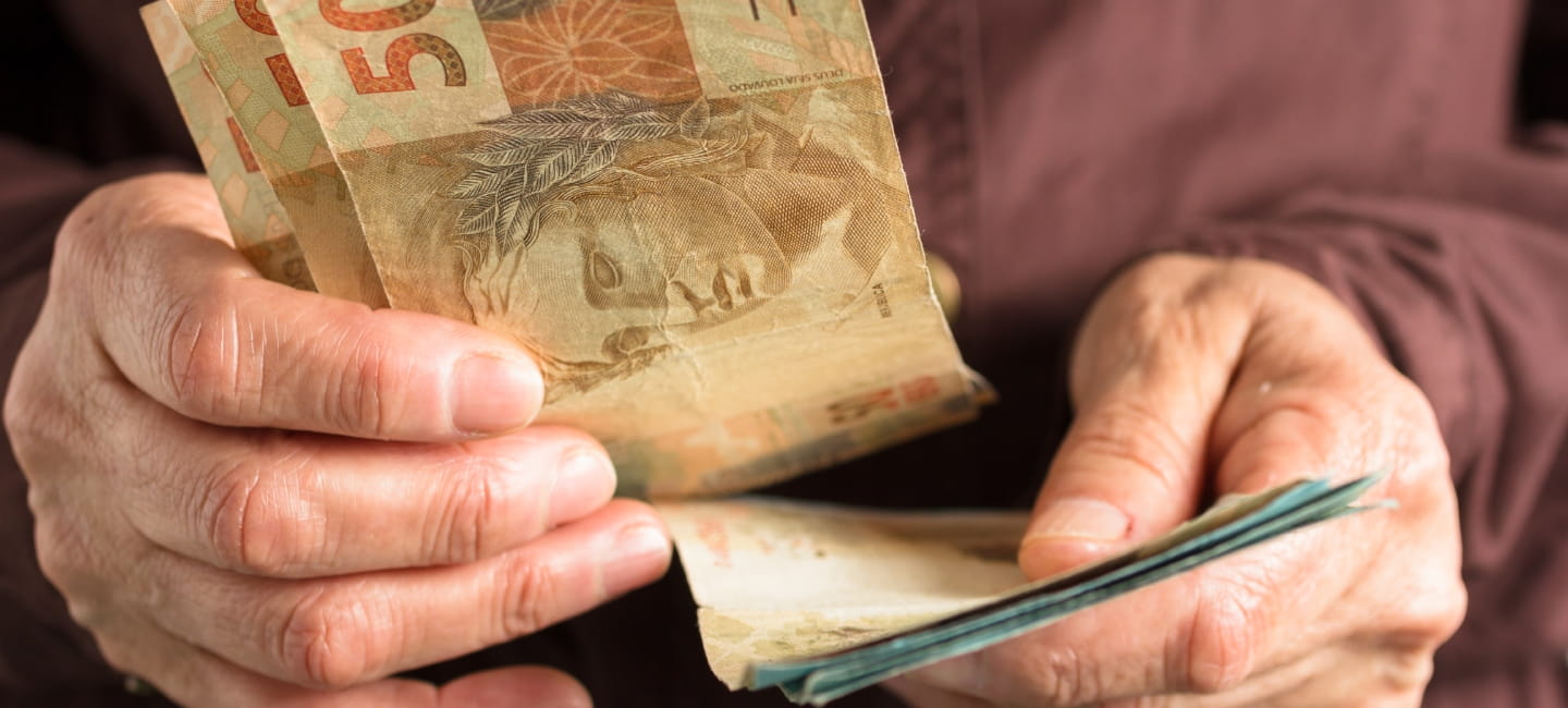 Brazilian currency: Real. Money from Brazil. Front view senior person holding bills.