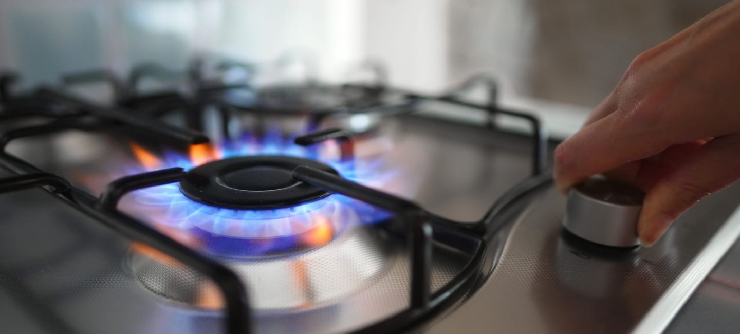 Woman turning on the gas burner on the stove.