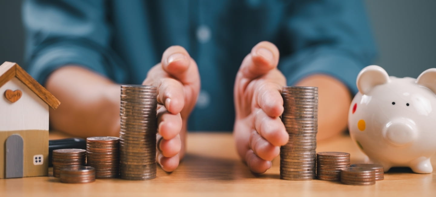 Divorce law and inheritance separation concept. Hand separate saving money, finance, home loan, debt return with piggybank and wood house. Bank business investment. Man separate stack coin on table.