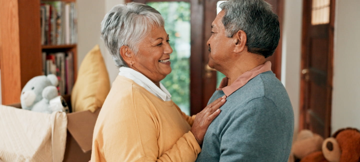 Love, moving and senior couple in home with hugging for happiness with new property for retirement. Smile, bonding and elderly man and woman embracing for new house with cardboard box together.