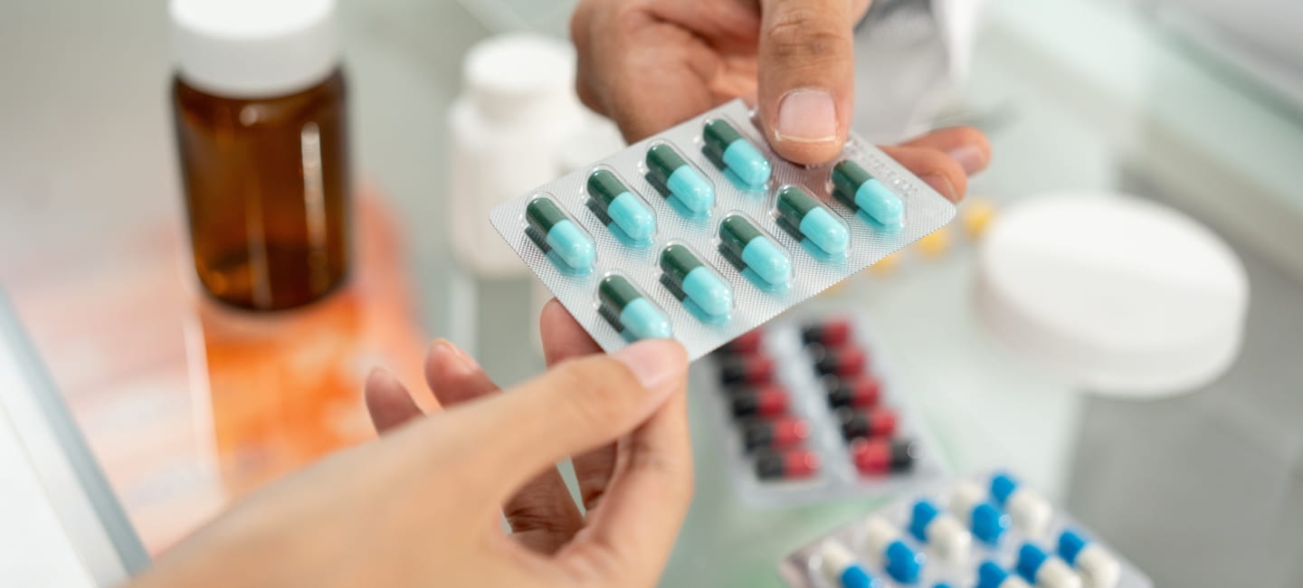 Pharmacist recommends medicines to customers. Asking the questions of medication. Professional Asian male pharmacist giving prescription medications to female patient customers at drugstore shelves.