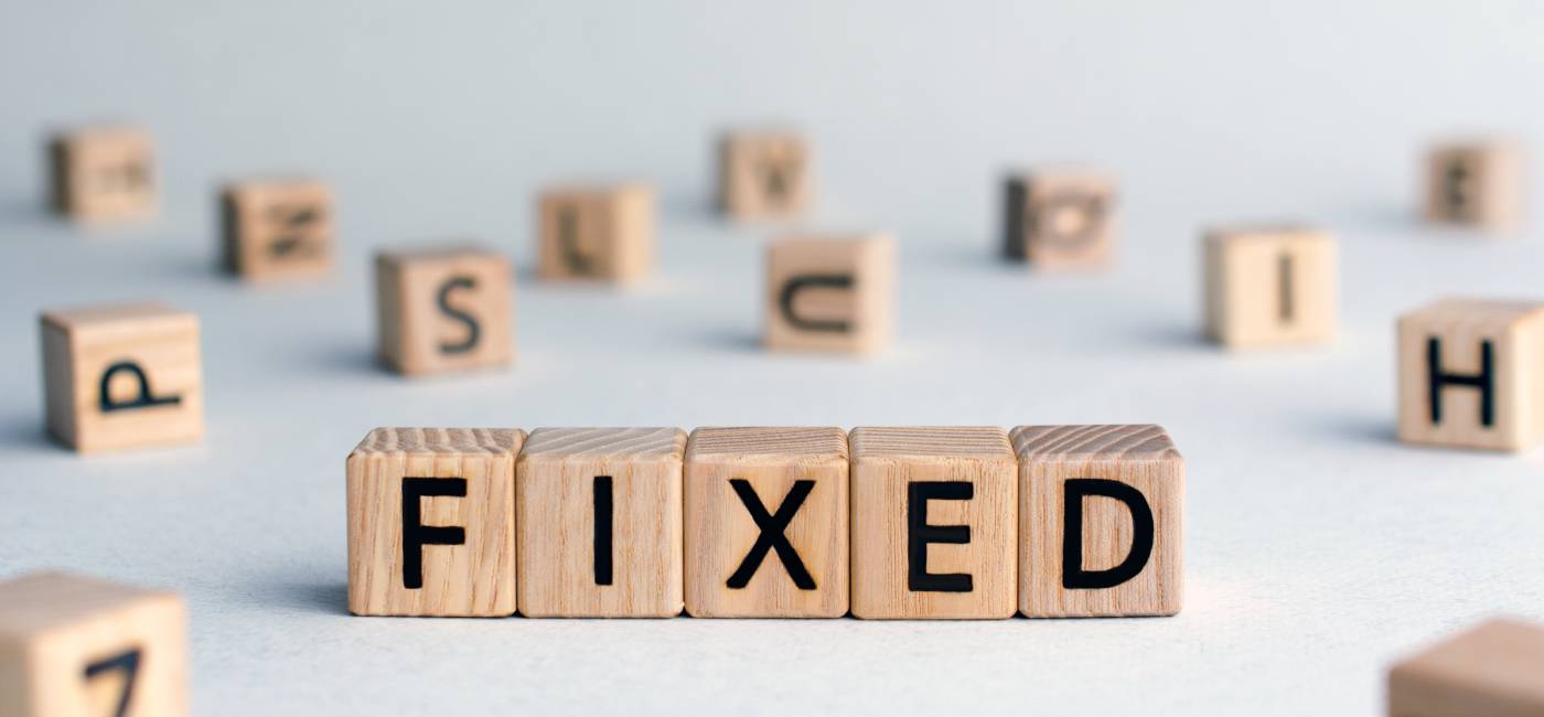 Fixed - word from wooden blocks with letters, fixed interest rates or costs concept, random letters around, top view on wooden background