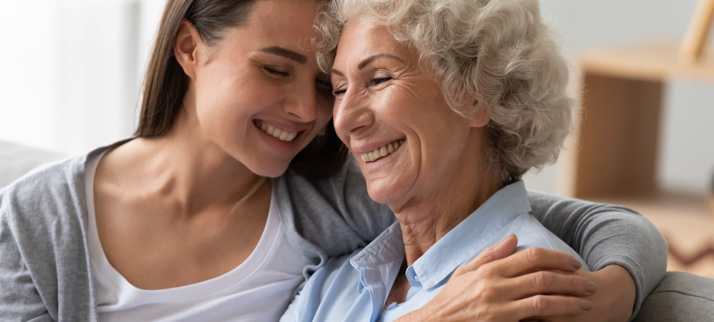 Positive smiling old grandma mother and young adult granddaughter daughter bonding at home, happy two generation women family laughing hugging having fun enjoying time together at reunion meeting