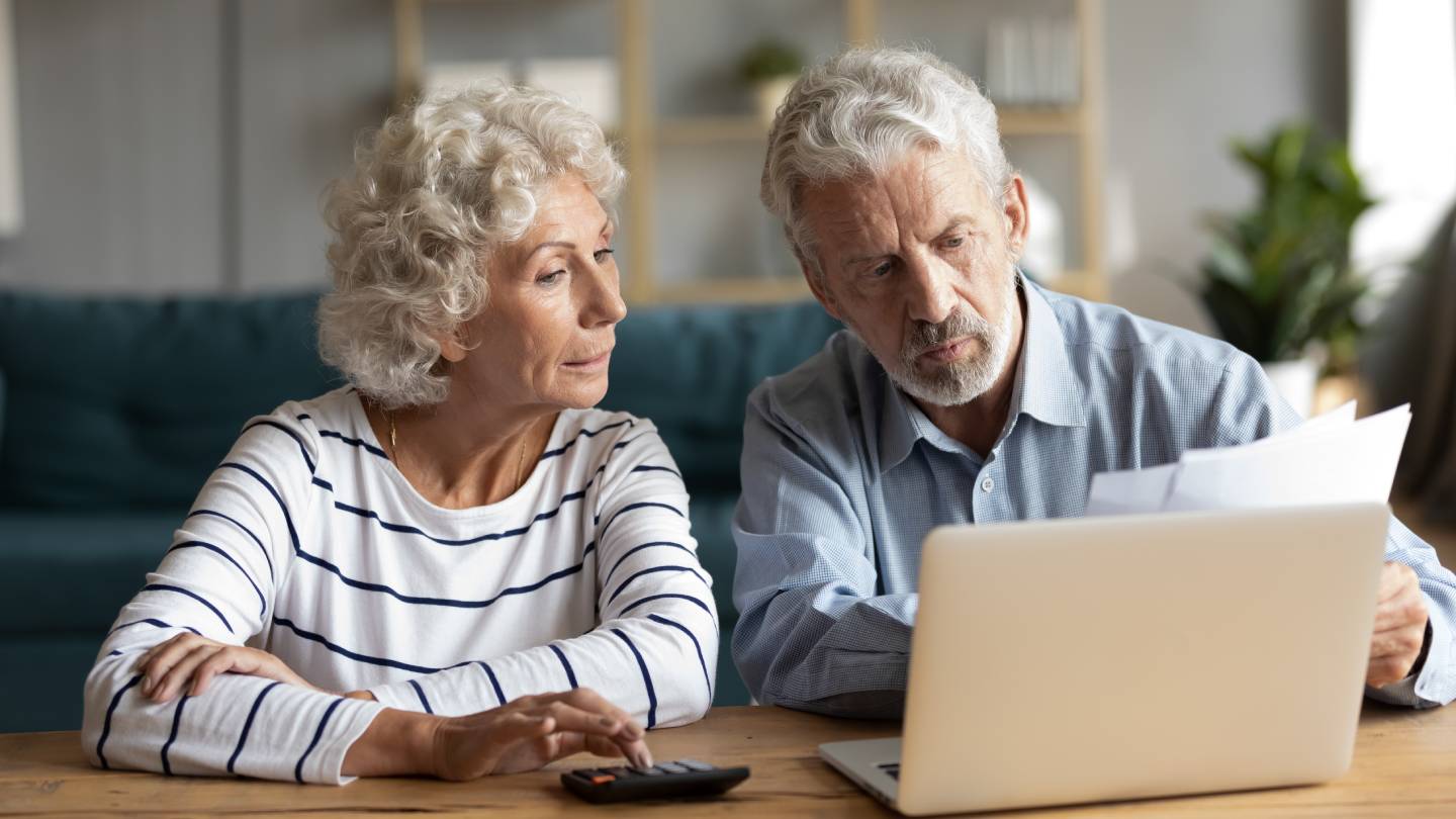 Mature couple sitting at a table reading a letter