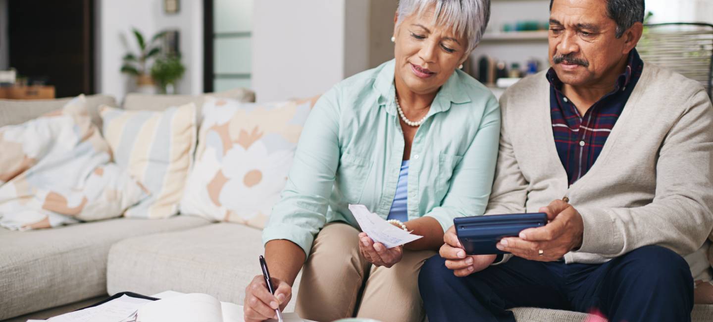 mature Husband and wife working out a budget while sitting on the living room sofa
