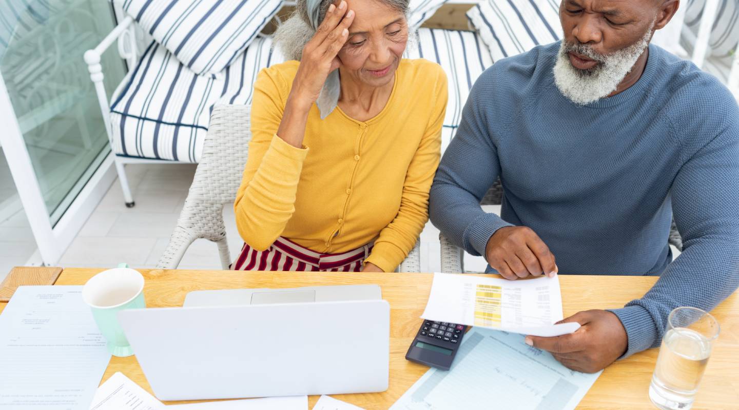 Focused senior couple on a laptop and looking at statements"