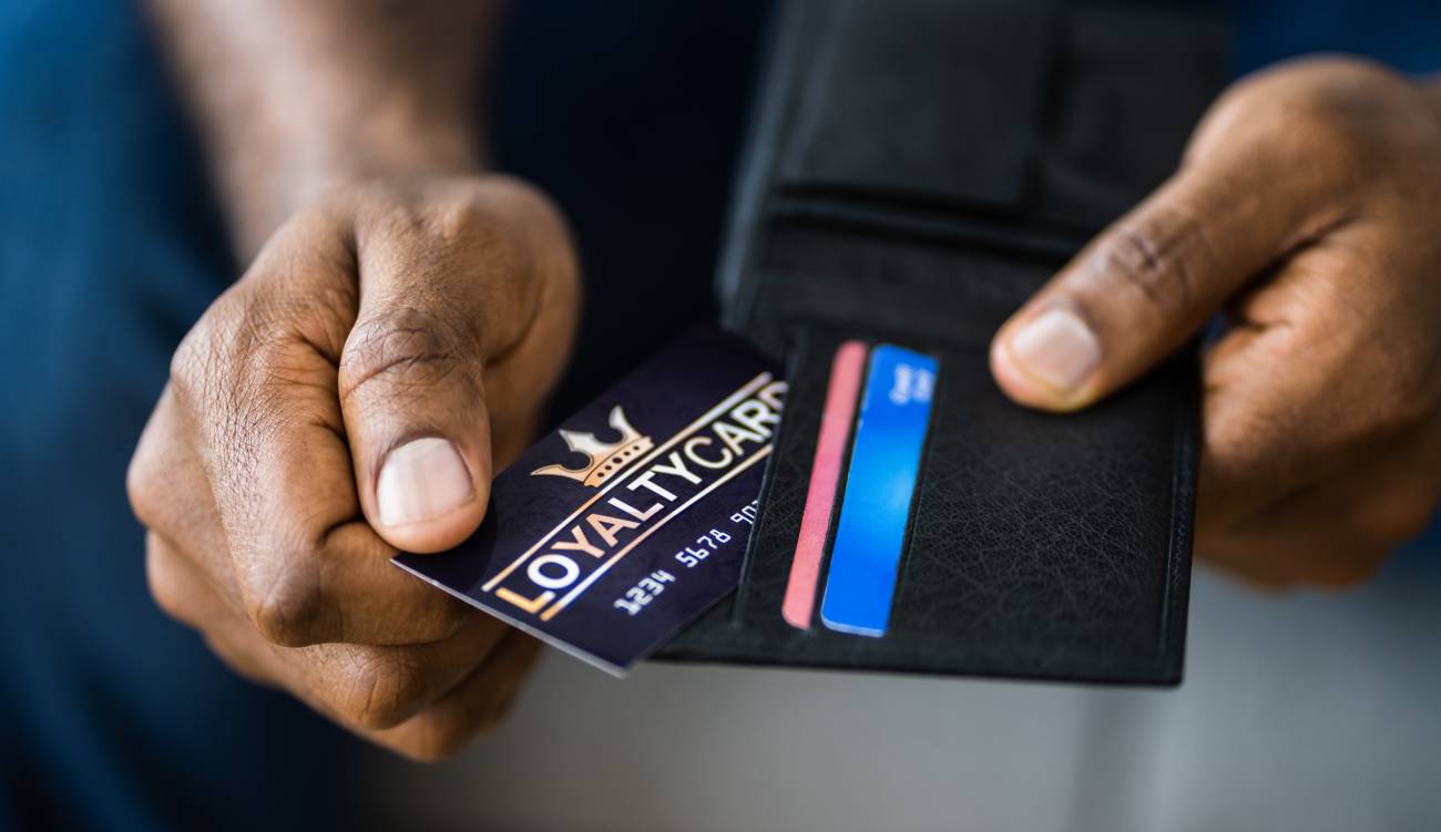 A male hand taking out his loyalty cards out of his black wallet