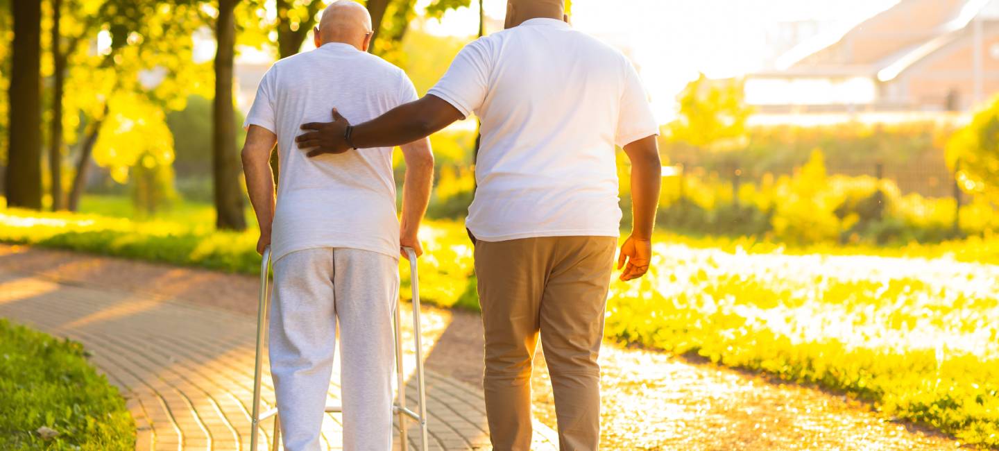 Professional nurse and patient walking outdoor at sunset.