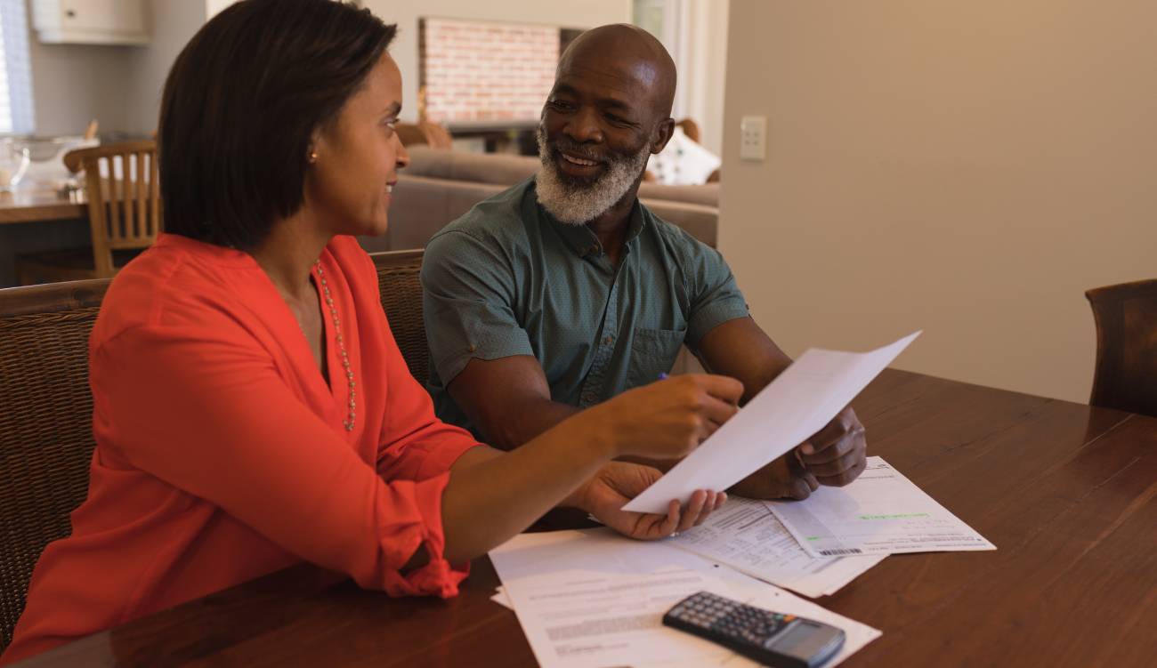 Side view of an active happy senior couple discussing over invoices in the living room at home