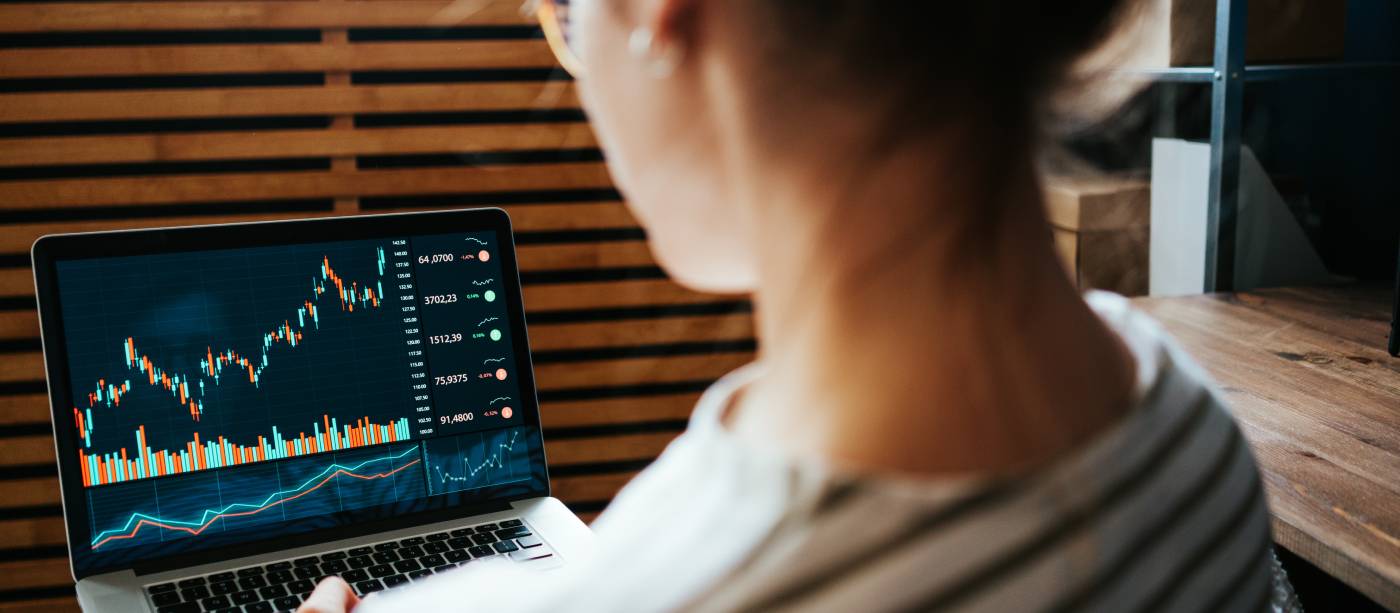 Woman investing in world stock market, using her laptop and online trading soft from home