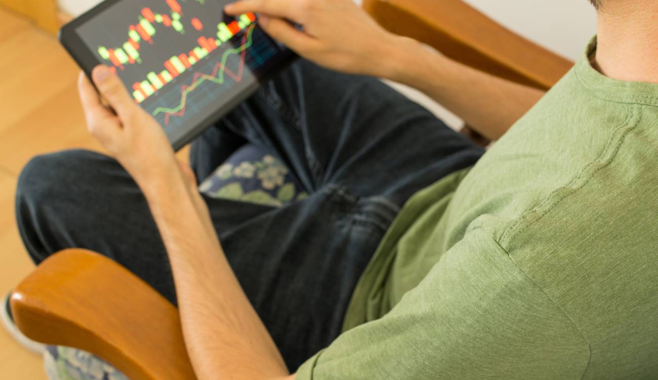 Young man holding a tablet and investing in the global stock market. Trading concept.