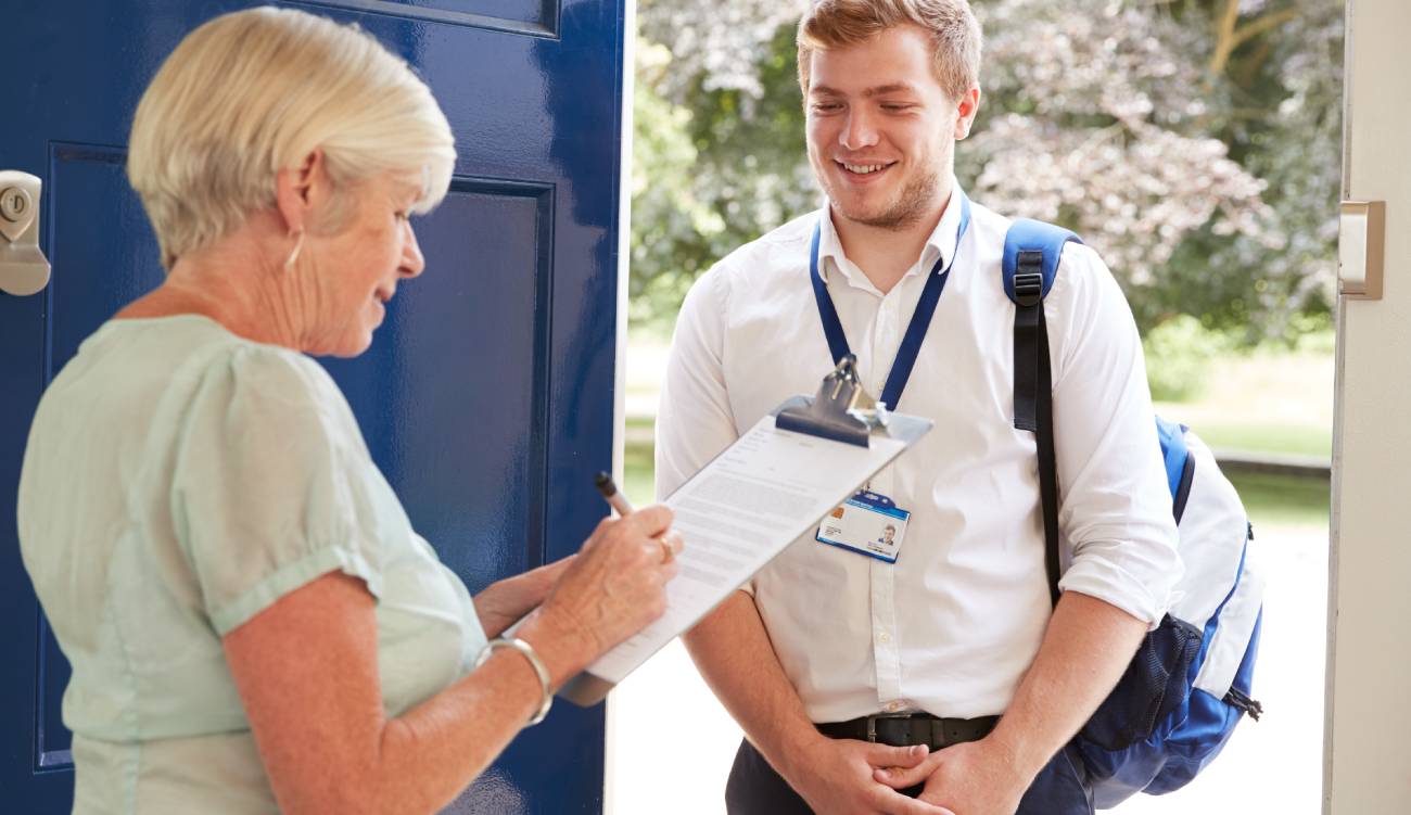 Senior woman filling in survey for visitor at her front door