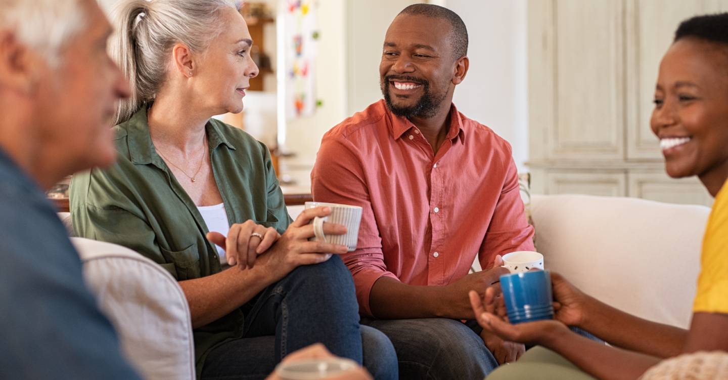 Cheerful multiethnic group of people enjoying a cup of tea while talking to each other.