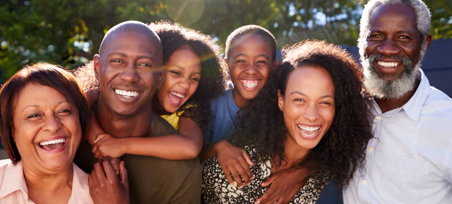 Outdoor Portrait Of Multi-Generation Family In Garden At Home Against Flaring Sun