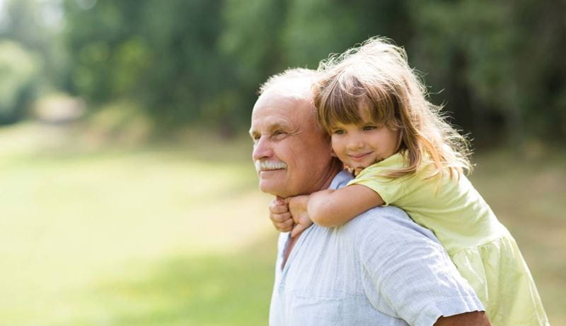 Little child girl hugs grandpa On Walk in the summer outdoors. Concept of friendly family.